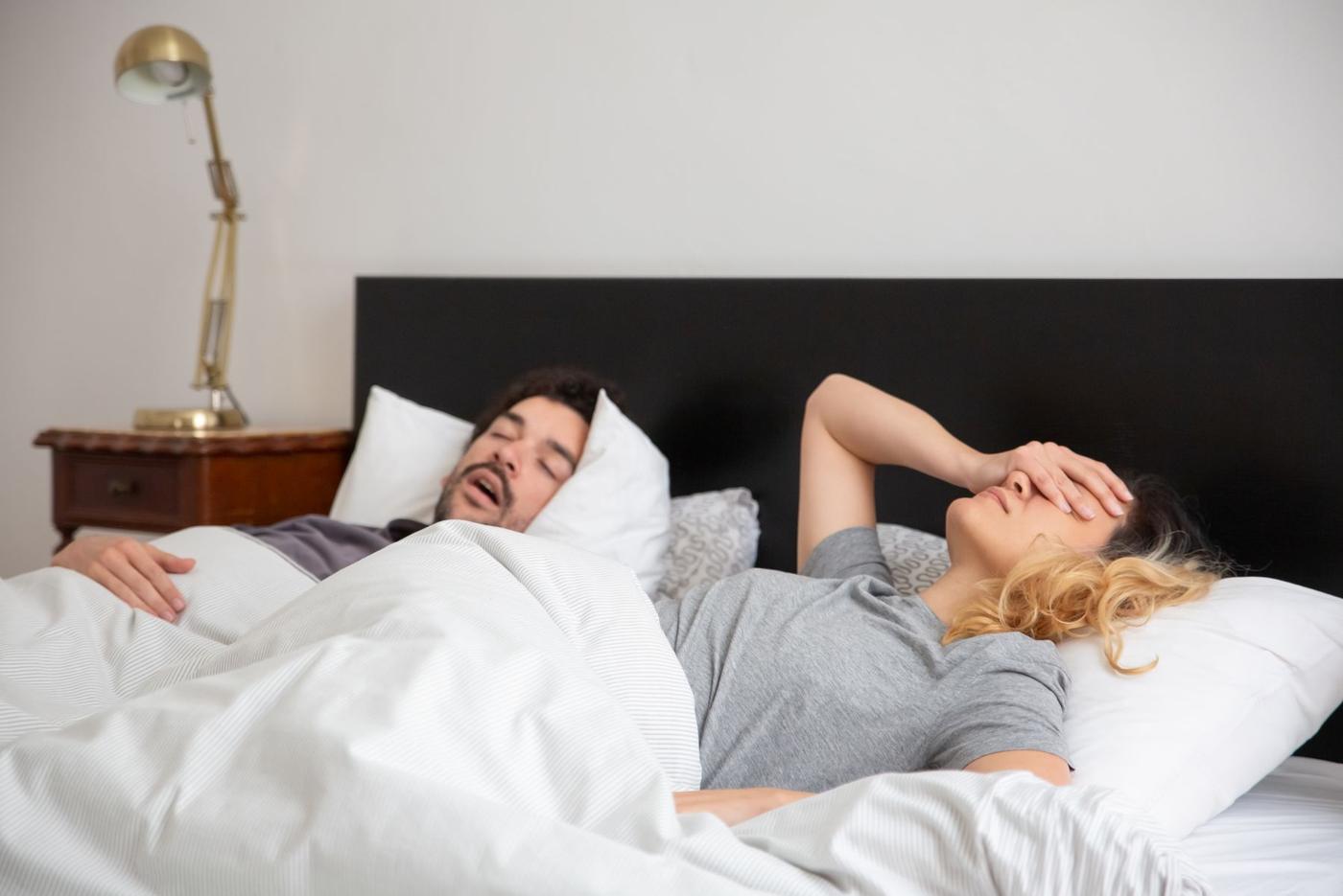 Homem a ressonar na cama e a companheira acordada
