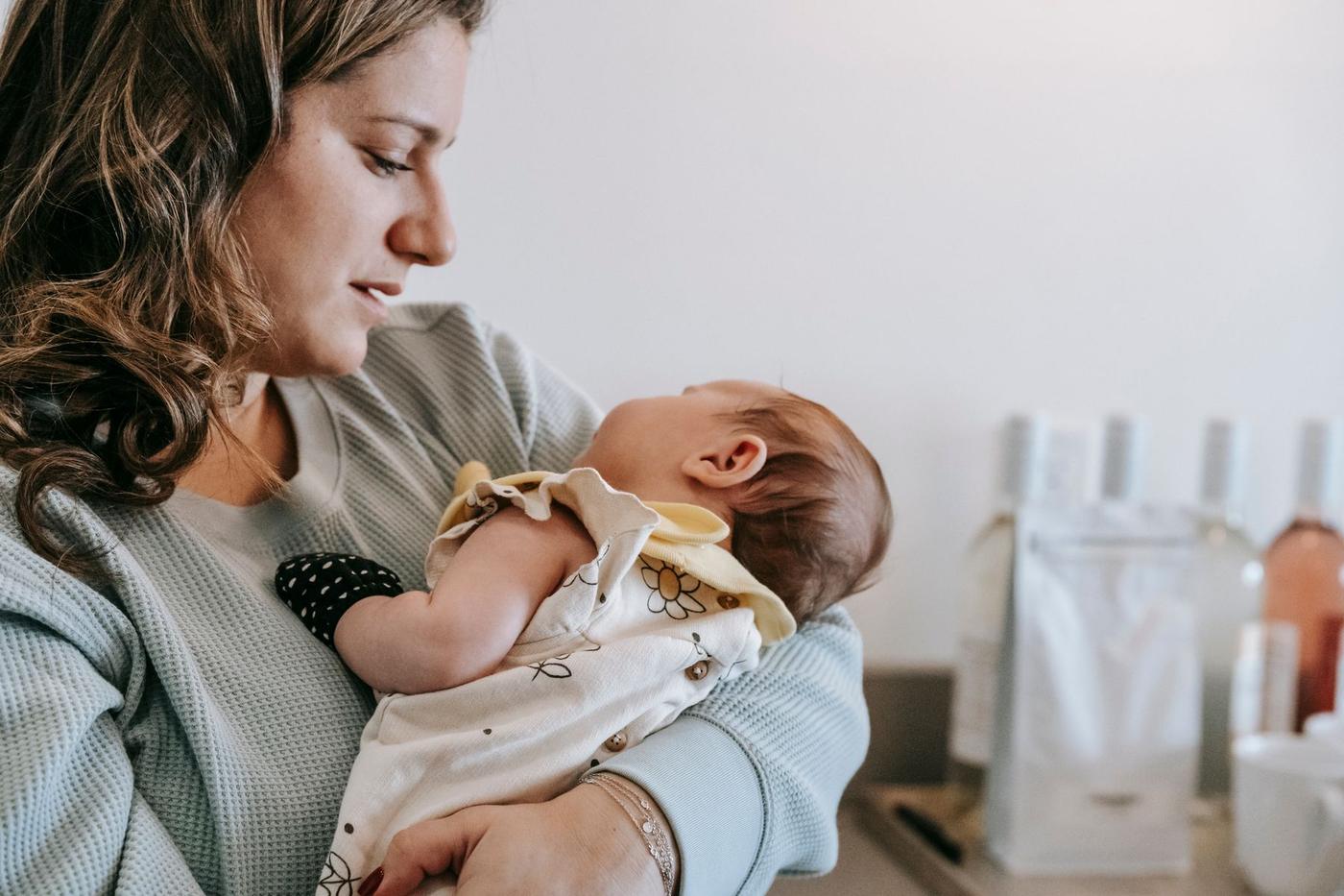 Mãe pensativa com o bebé recém-nascido ao colo
