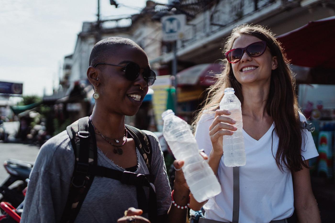 Duas viajantes na rua com garrafas de água