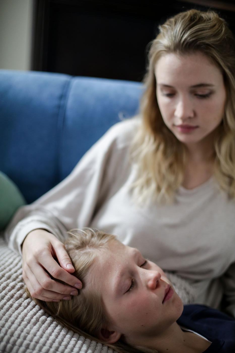 Mãe a cuidar do filho deitado no sofá