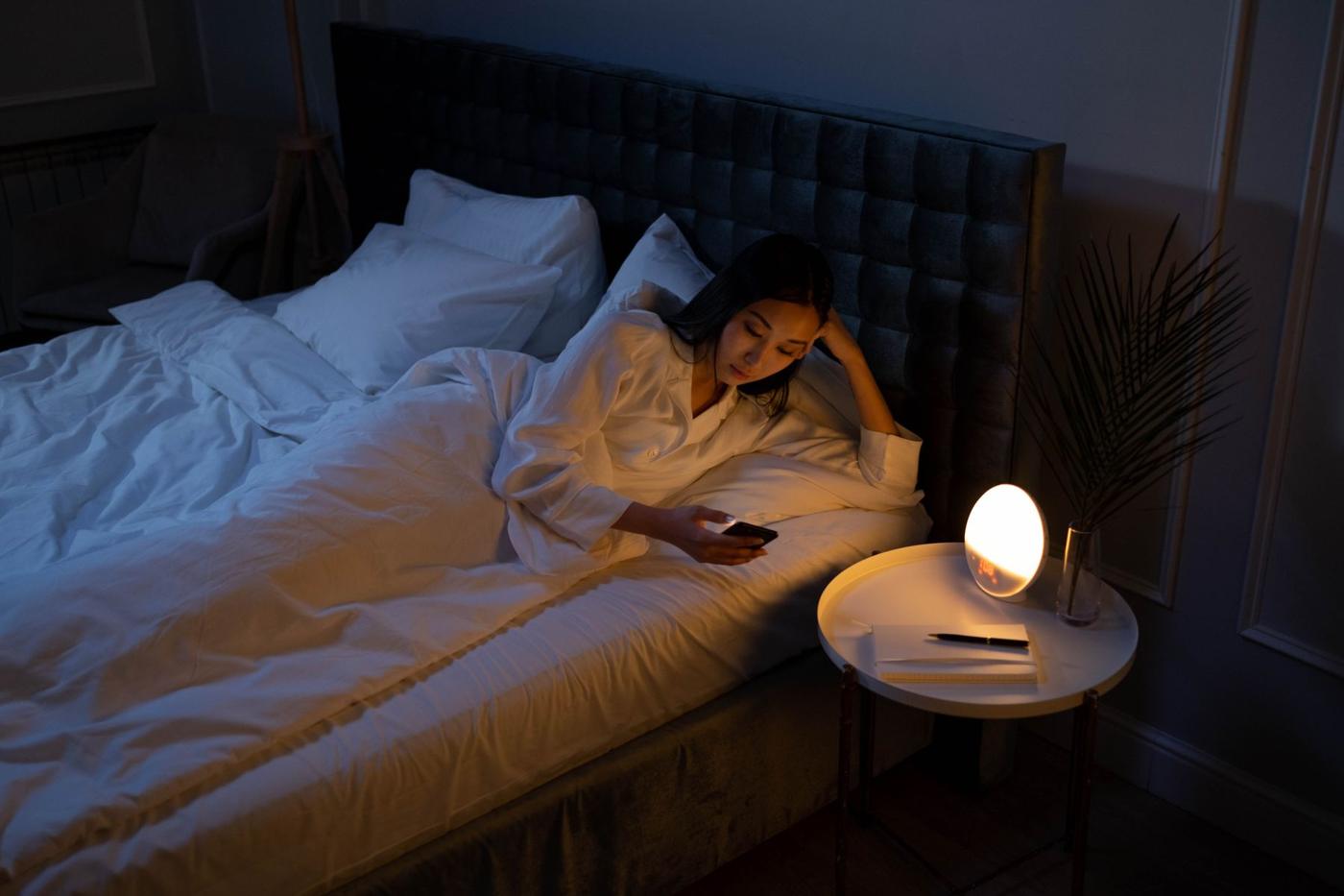 Pessoa acordada na cama à noite, com o telemóvel