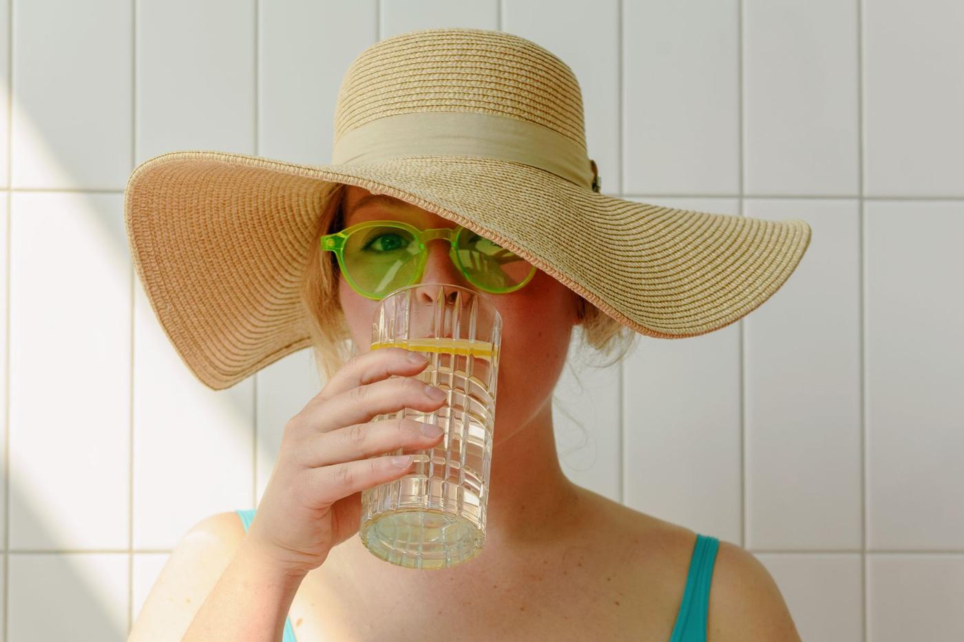 Mulher de chapéu de palha a beber água