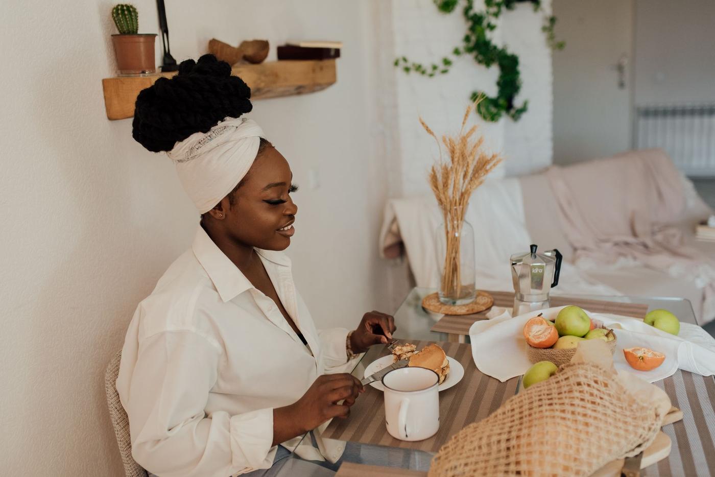 Mulher a tomar o pequeno-almoço com fruta em casa