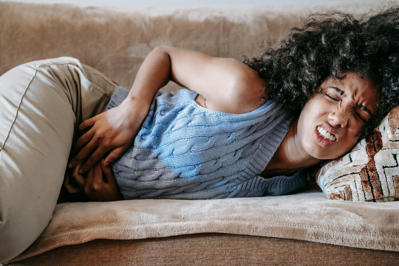 Mulher deitada no sofá com dor de barriga