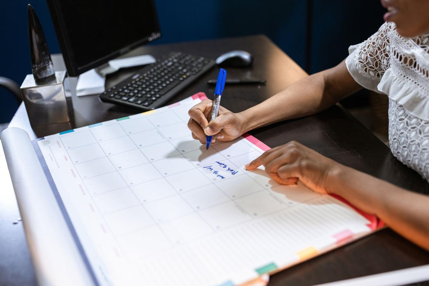 Mulher a assinalar datas num calendário de parede
